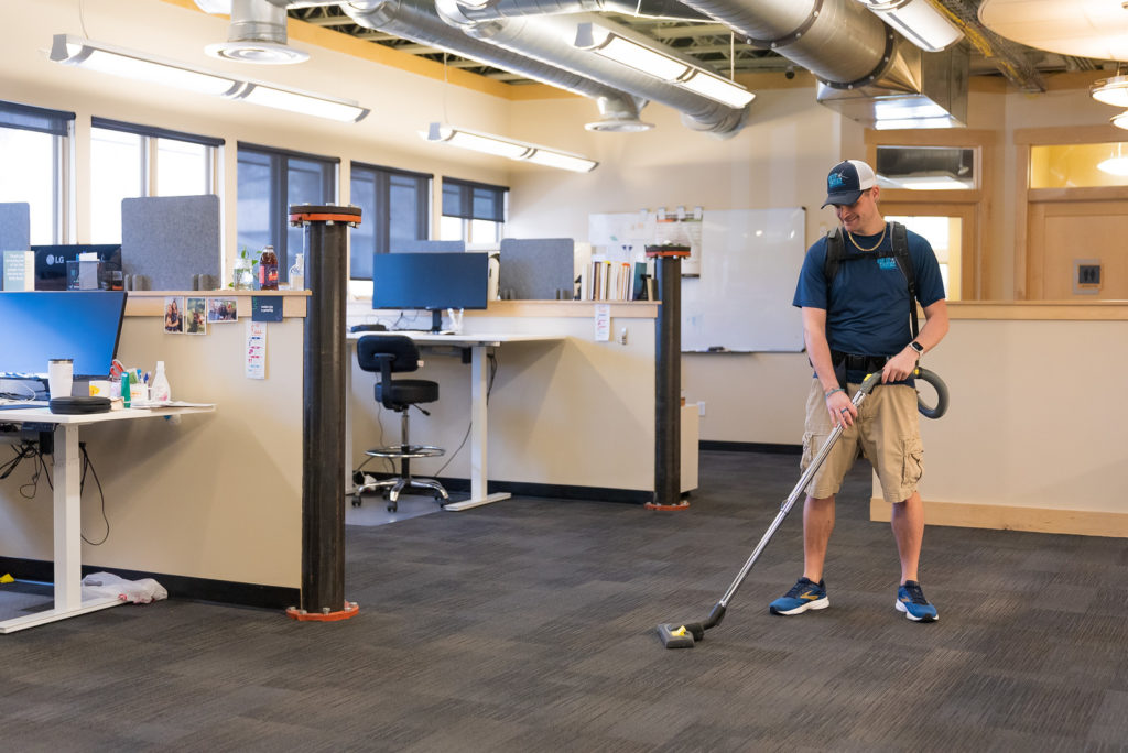 man vacuuming floor in office