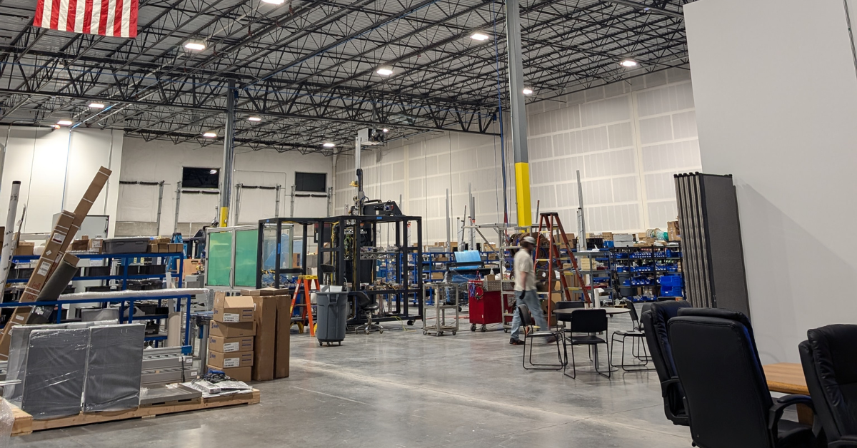 Interior of a clean and organized industrial facility with workstations, equipment, and visible maintenance areas, representing a commercial cleaning environment.